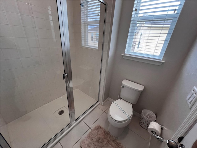 bathroom featuring toilet, tile patterned floors, and a shower with door