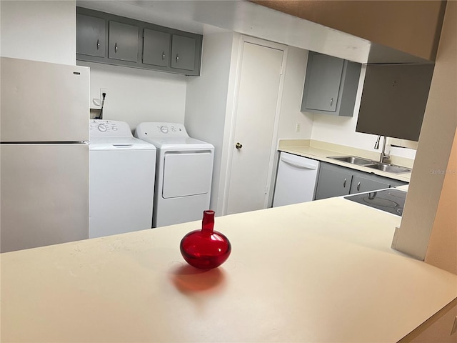 kitchen with sink, white appliances, gray cabinets, and washing machine and clothes dryer