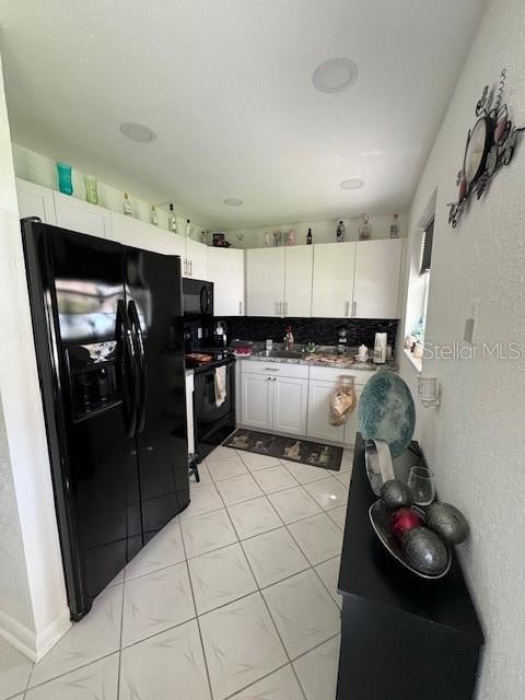 kitchen with black appliances, white cabinets, tasteful backsplash, and light tile floors