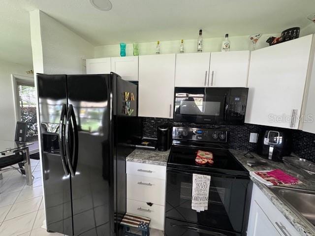 kitchen featuring tasteful backsplash, stone counters, light tile flooring, black appliances, and white cabinets