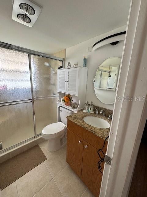 bathroom with tile floors, a shower with shower door, oversized vanity, and toilet