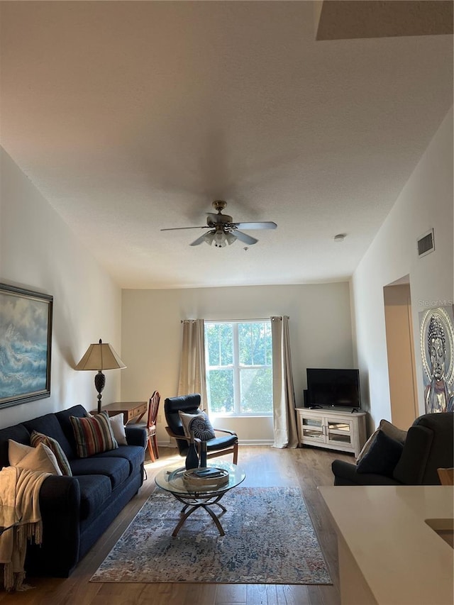 living room with hardwood / wood-style floors, ceiling fan, and vaulted ceiling