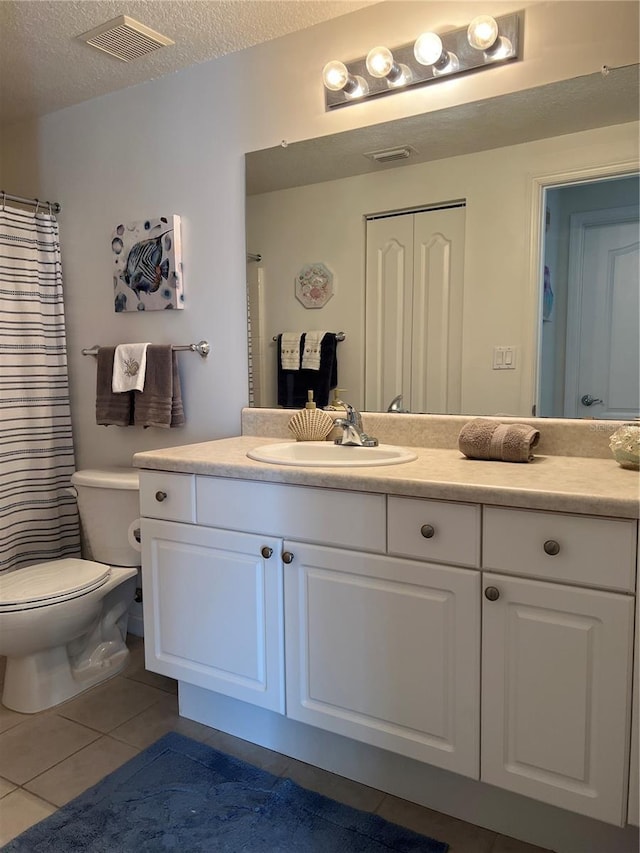 bathroom with tile patterned flooring, vanity, toilet, and a textured ceiling