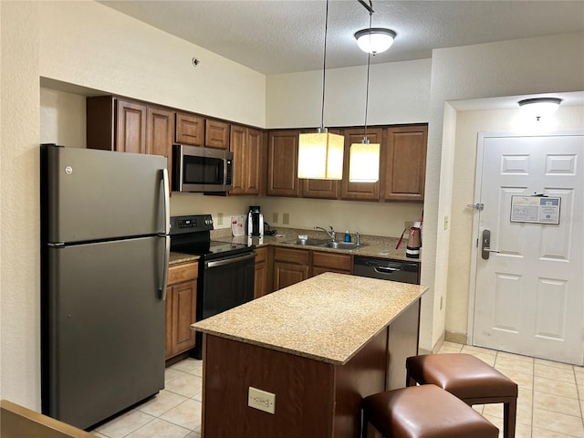 kitchen with pendant lighting, a center island, black appliances, sink, and light tile patterned floors