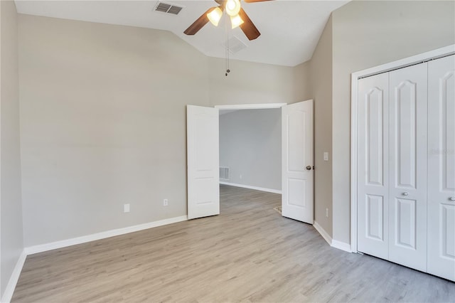 unfurnished bedroom featuring ceiling fan, a closet, high vaulted ceiling, and light wood-type flooring