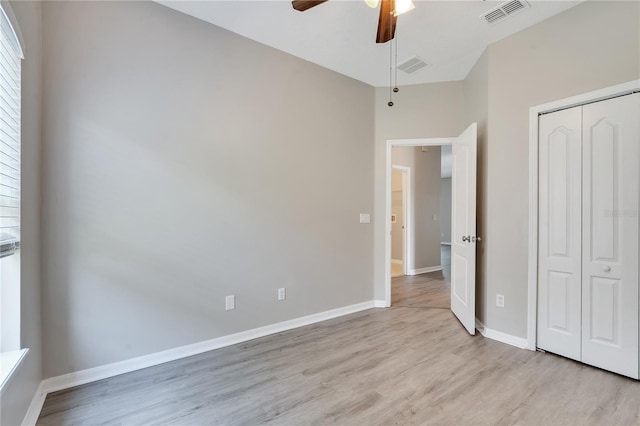 unfurnished bedroom featuring ceiling fan, a closet, and light wood-type flooring