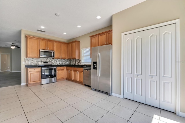 kitchen featuring decorative backsplash, ceiling fan, light tile patterned floors, and stainless steel appliances