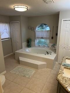 bathroom featuring tile patterned floors, a tub to relax in, and vanity