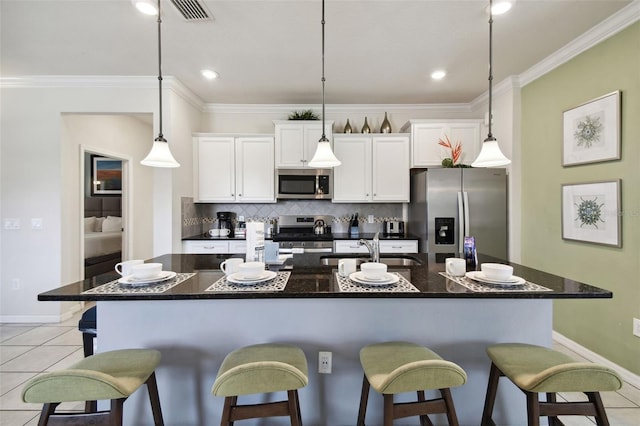 kitchen featuring white cabinetry, a center island with sink, light tile patterned flooring, and appliances with stainless steel finishes