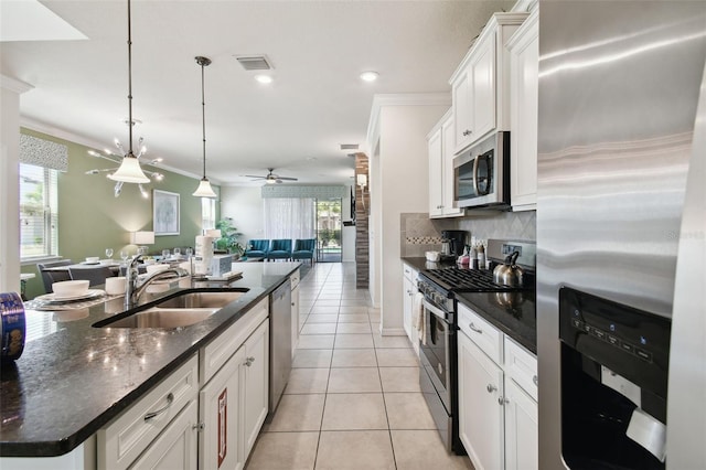 kitchen with appliances with stainless steel finishes, ceiling fan, sink, white cabinetry, and an island with sink