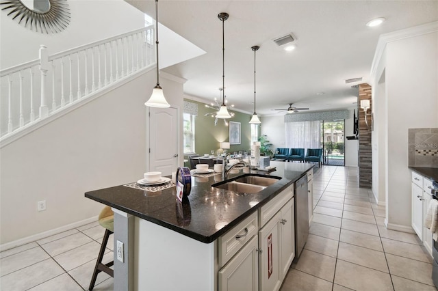 kitchen featuring dishwasher, a breakfast bar, sink, ceiling fan, and an island with sink