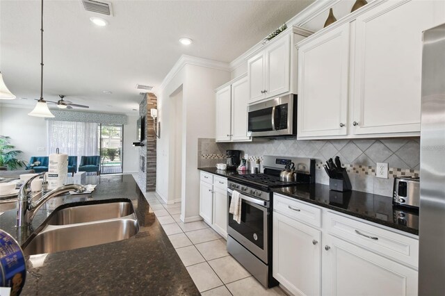 kitchen with white cabinetry, sink, stainless steel appliances, and decorative light fixtures