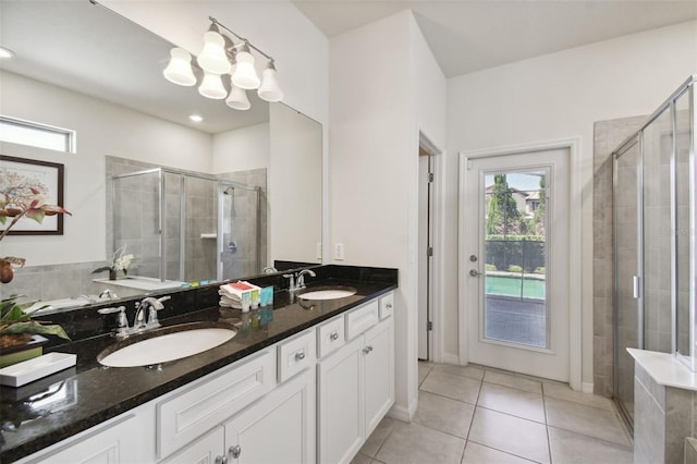 bathroom featuring tile patterned floors, vanity, a shower with shower door, and an inviting chandelier