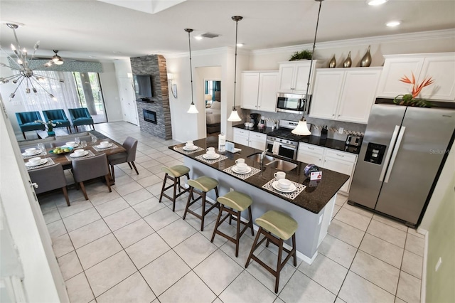 kitchen featuring white cabinets, a breakfast bar, stainless steel appliances, and a kitchen island with sink