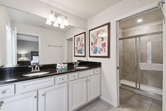 bathroom featuring tile patterned floors, a shower with door, vanity, and a textured ceiling