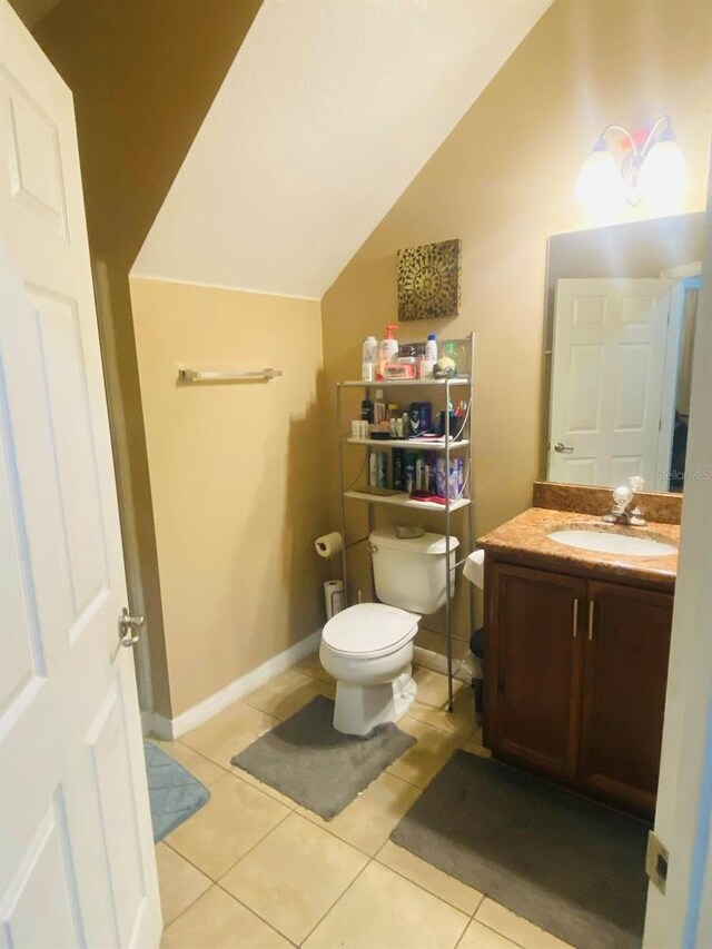 bathroom featuring tile patterned flooring, vanity, toilet, and vaulted ceiling