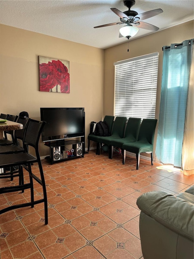 living room with tile patterned flooring, ceiling fan, and a textured ceiling