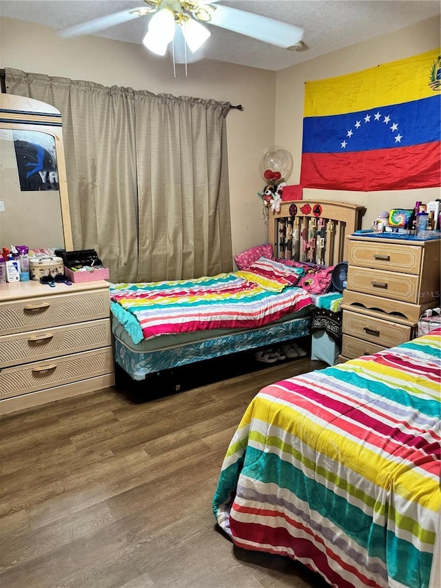 bedroom with ceiling fan, hardwood / wood-style floors, and a textured ceiling