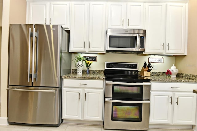 kitchen featuring dark stone countertops, white cabinets, and stainless steel appliances