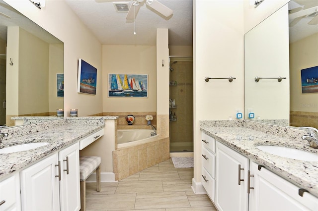 bathroom with ceiling fan, separate shower and tub, a textured ceiling, and vanity