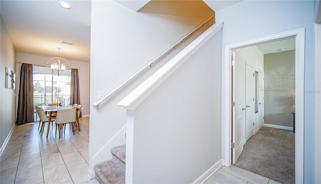 stairs featuring tile patterned flooring and a notable chandelier