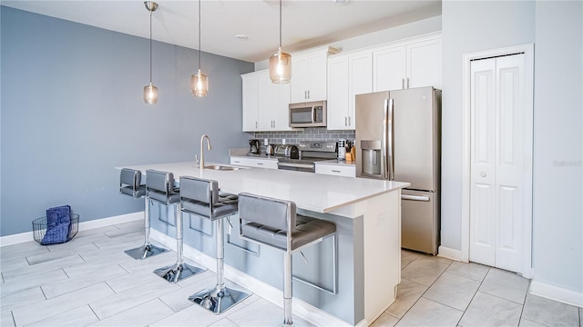 kitchen featuring a kitchen island with sink, a breakfast bar, white cabinets, and stainless steel appliances