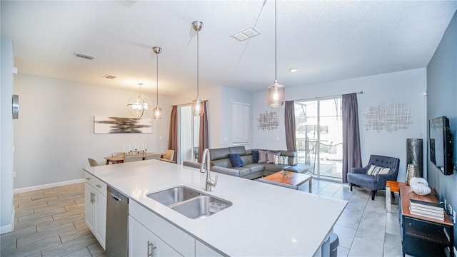 kitchen featuring a kitchen island with sink, sink, pendant lighting, dishwasher, and white cabinetry