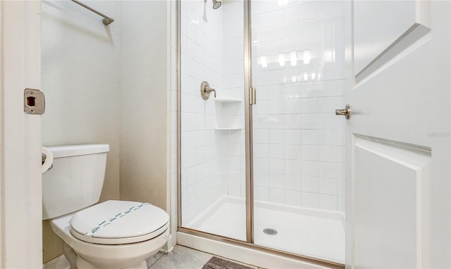 bathroom featuring tile patterned floors, a shower with shower door, and toilet