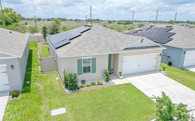 single story home with a garage, a front yard, and solar panels