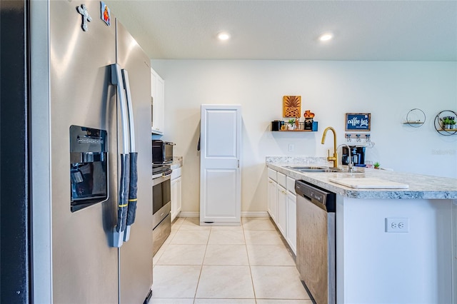 kitchen featuring sink, light tile patterned floors, kitchen peninsula, stainless steel appliances, and white cabinets