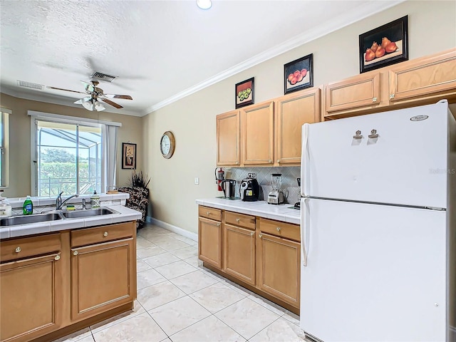 kitchen featuring ceiling fan, sink, tile countertops, and white fridge