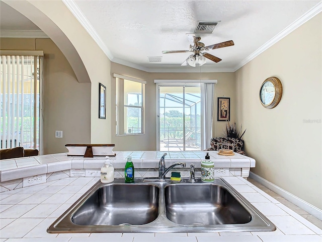 kitchen featuring tile counters, crown molding, and sink