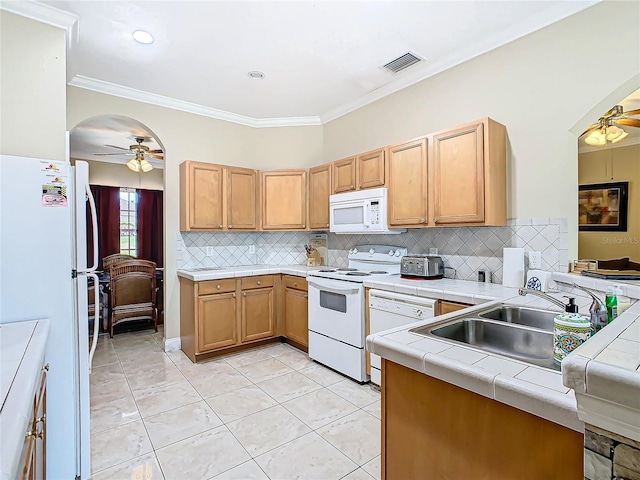 kitchen with ceiling fan, white appliances, crown molding, sink, and tile counters