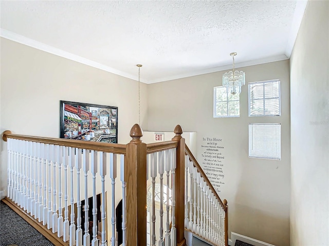 staircase with ornamental molding, a chandelier, and a textured ceiling