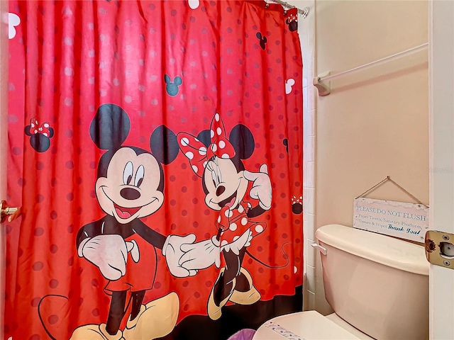 bathroom with toilet and curtained shower