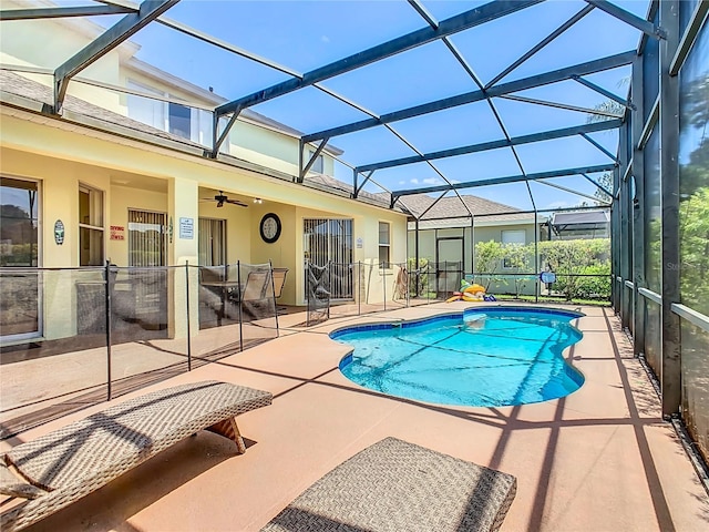 view of pool with glass enclosure, ceiling fan, and a patio area