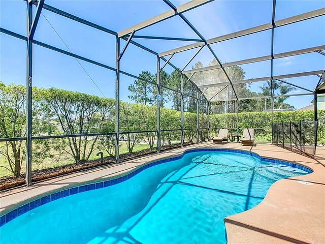 view of pool with glass enclosure and a patio