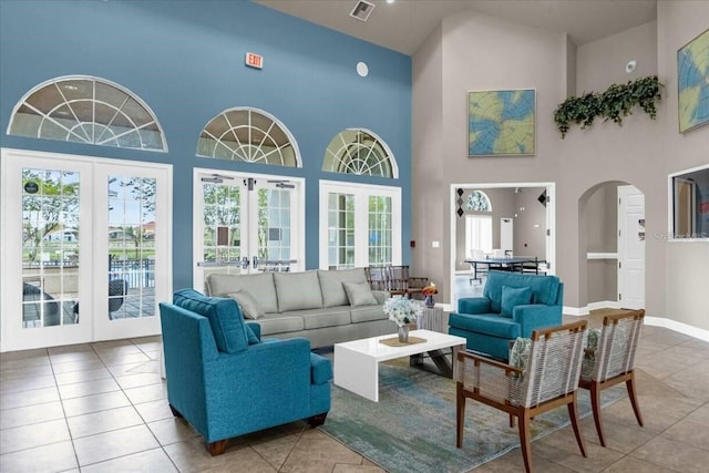 tiled living room with french doors and high vaulted ceiling