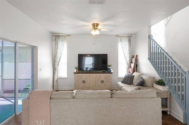 living room with a textured ceiling, ceiling fan, dark hardwood / wood-style flooring, and plenty of natural light