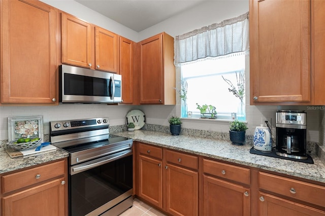 kitchen with light stone counters, light tile patterned flooring, and stainless steel appliances