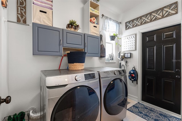 clothes washing area featuring washing machine and clothes dryer, light tile patterned floors, and cabinets