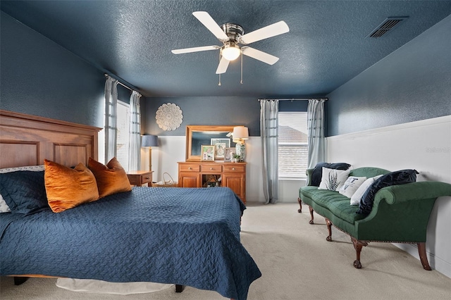 carpeted bedroom featuring ceiling fan and a textured ceiling