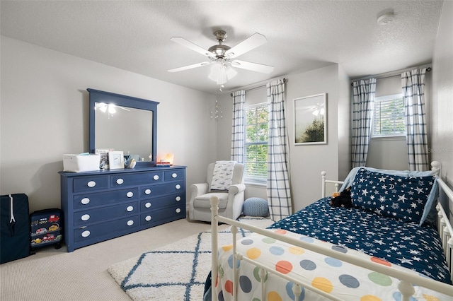 bedroom featuring a textured ceiling, light colored carpet, and ceiling fan