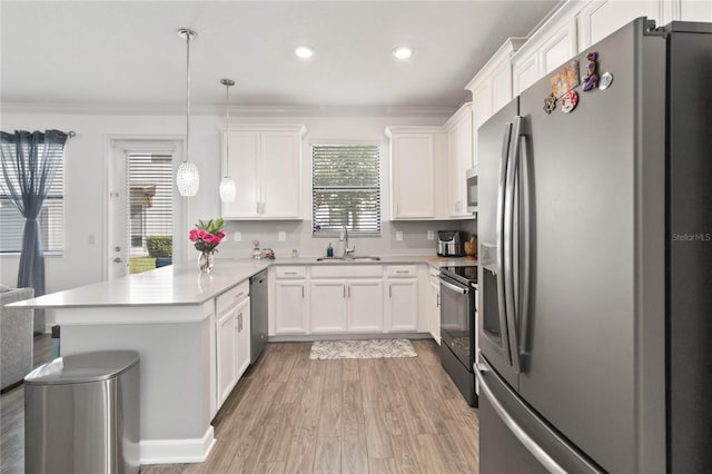 kitchen featuring sink, appliances with stainless steel finishes, kitchen peninsula, pendant lighting, and white cabinets