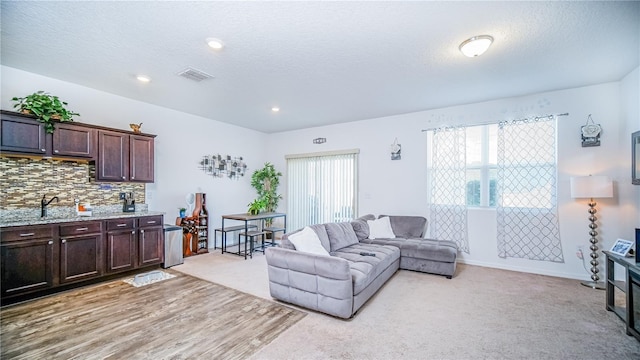 living room featuring a textured ceiling, sink, and light carpet