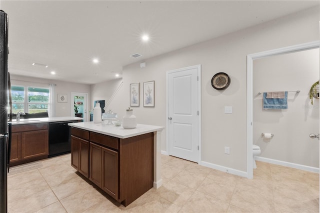 kitchen with dishwasher, a kitchen island, light tile patterned flooring, and sink