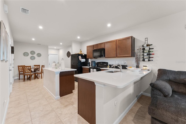 kitchen with kitchen peninsula, sink, light tile patterned floors, and black appliances