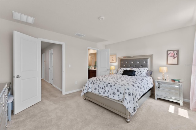 bedroom with connected bathroom and light colored carpet