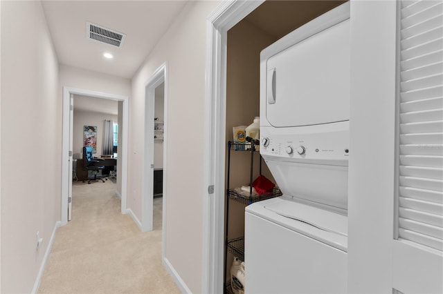 laundry area featuring stacked washer / dryer and light colored carpet