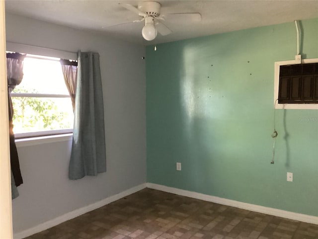 spare room with ceiling fan and dark tile floors